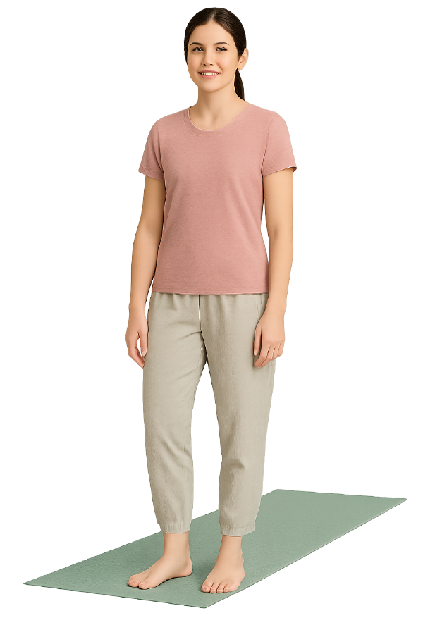 ヨガマットの上に立った、ピンクのスポーツウェアと、ベージュのドライパンツを着用した女性